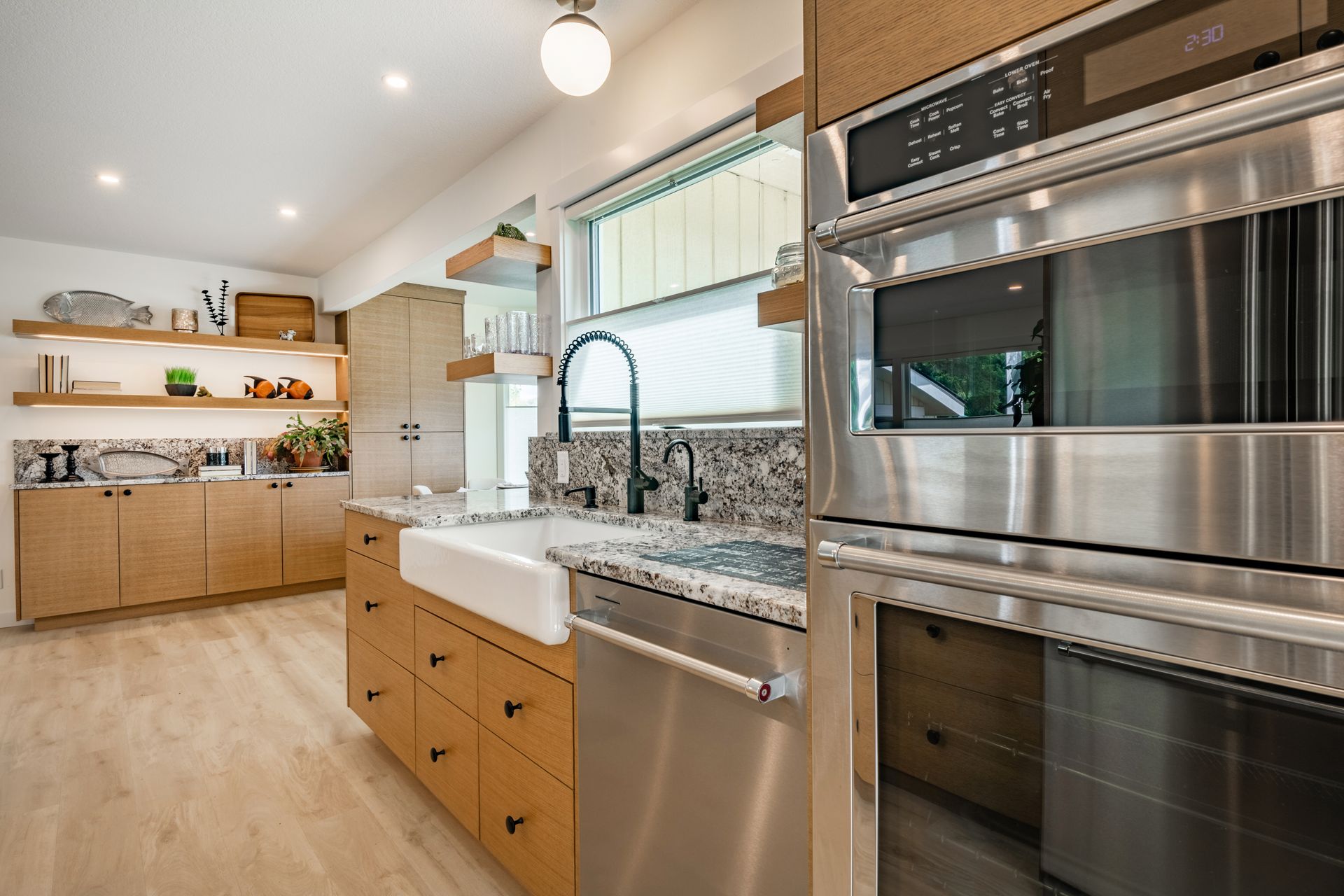 Modern kitchen with light wood cabinets, stainless steel appliances, and a farmhouse sink.