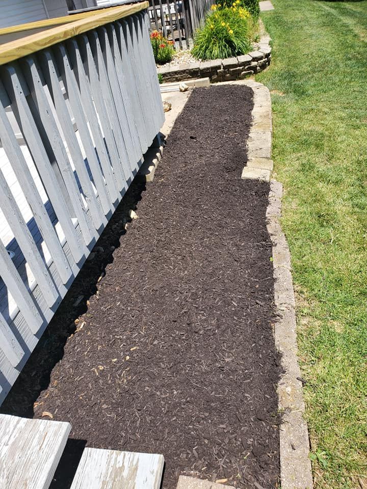 A walkway with mulch on the side of it next to a fence.