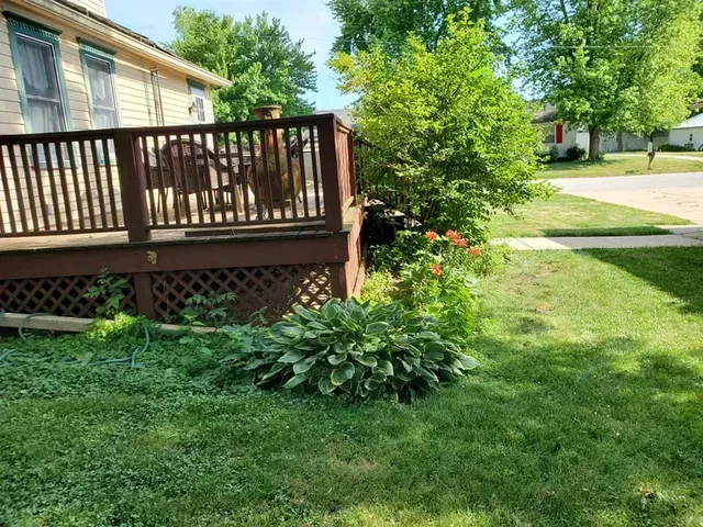 A house with a deck and a lawn in front of it.