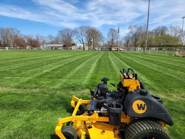 A yellow lawn mower is sitting on top of a lush green field.