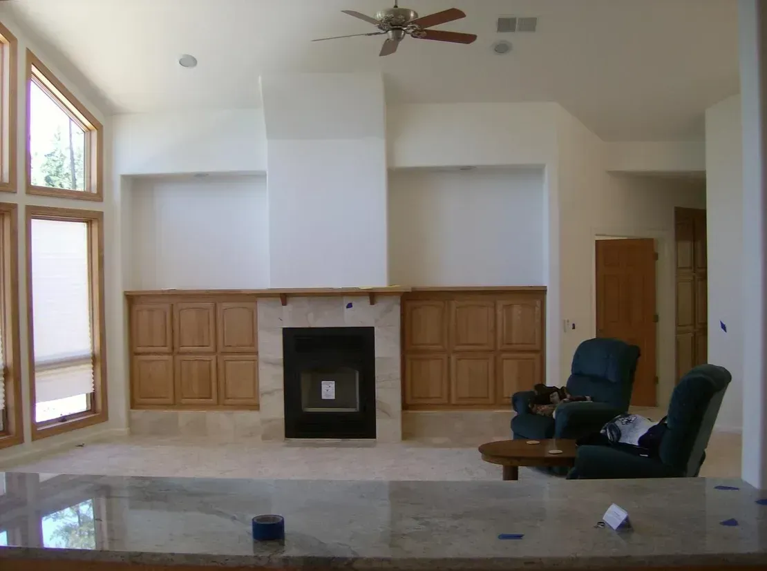 Living room with fireplace, cabinets, tall windows, and two recliners.