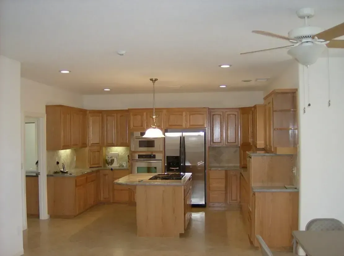 A kitchen with light wood cabinets, stainless steel appliances, and a central island with a stovetop.