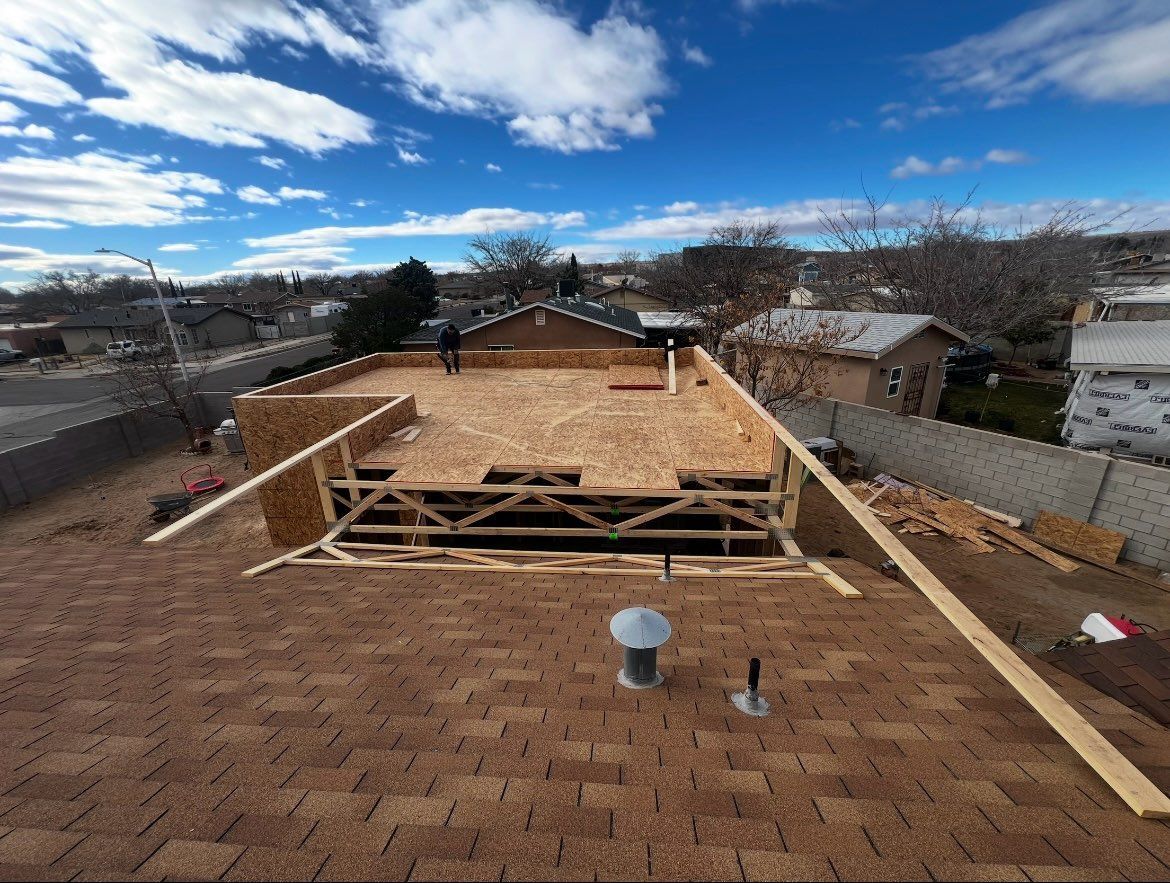 A pink box mounted on a red tile roof, supported by metal legs with wires. Trees and sky in the background.