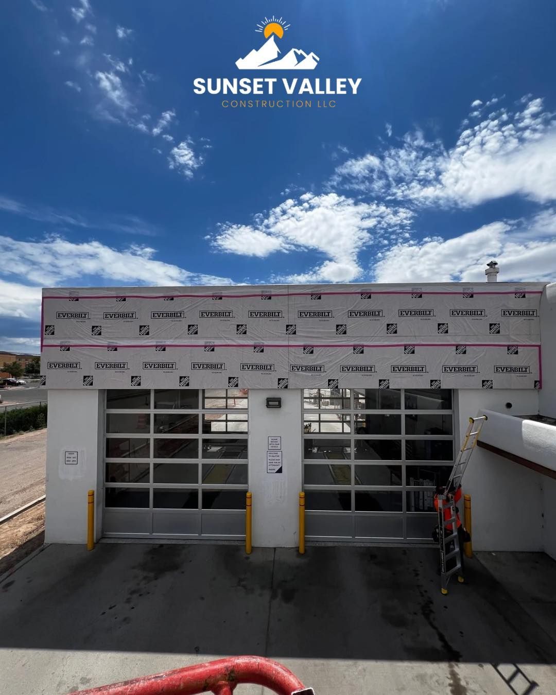 Sunset Valley building with glass garage doors, construction in progress, blue sky.