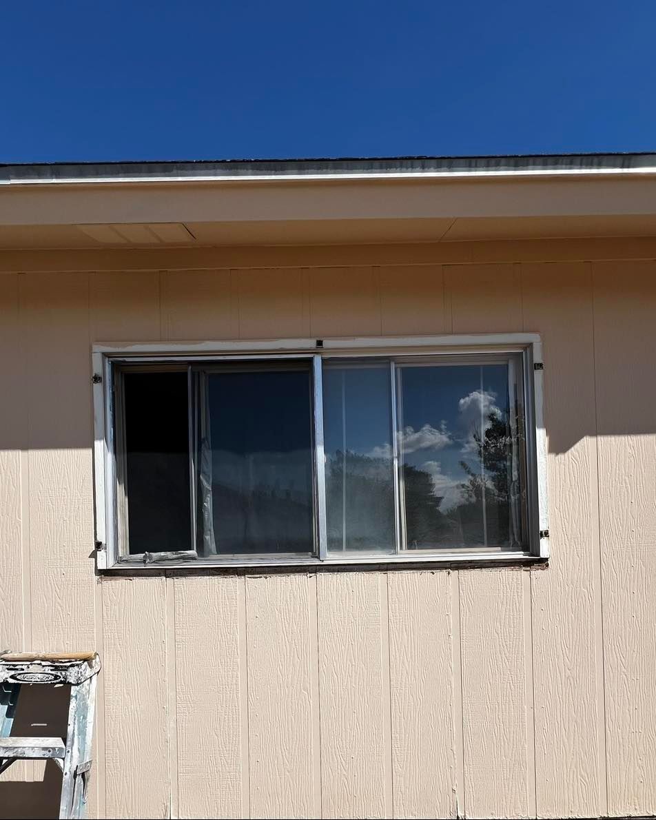 Sliding window on a beige building, blue sky reflected in the glass.