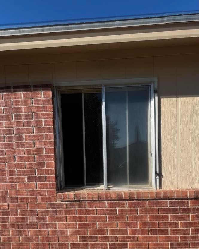 Brick building with a partially open sliding glass window.