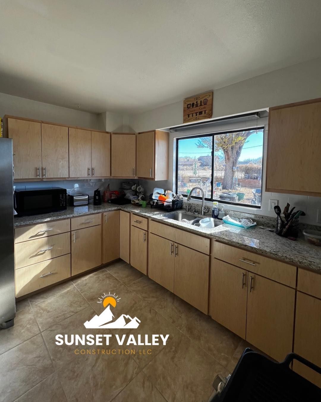 Kitchen with light wood cabinets, granite countertops, and a window overlooking a desert landscape.