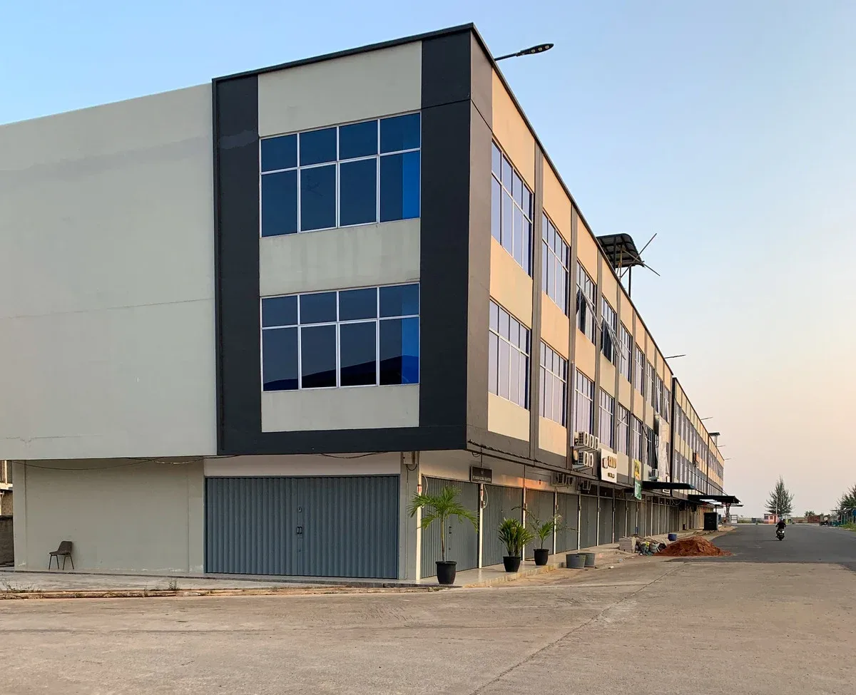 Two-story commercial building with blue-tinted windows, gray and white facade, and a closed metal storefront.