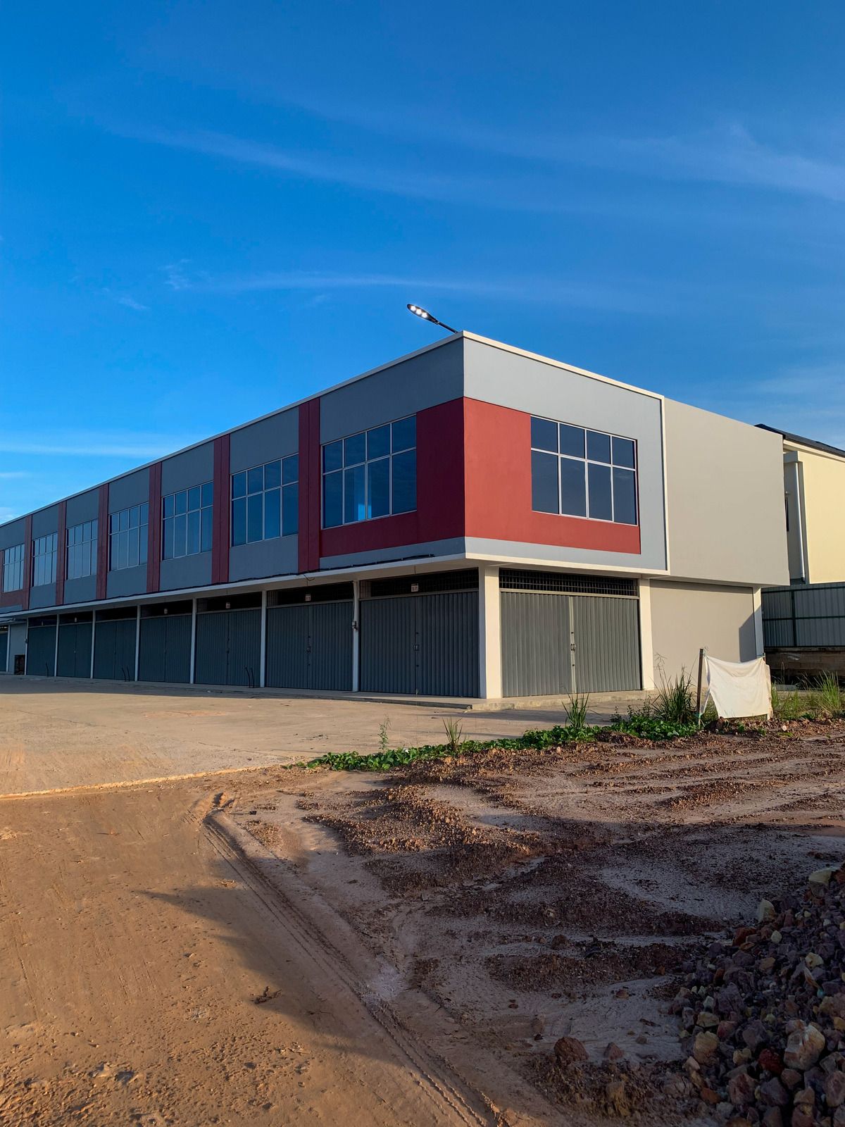 Modern commercial building with red and grey facade; blue sky background.