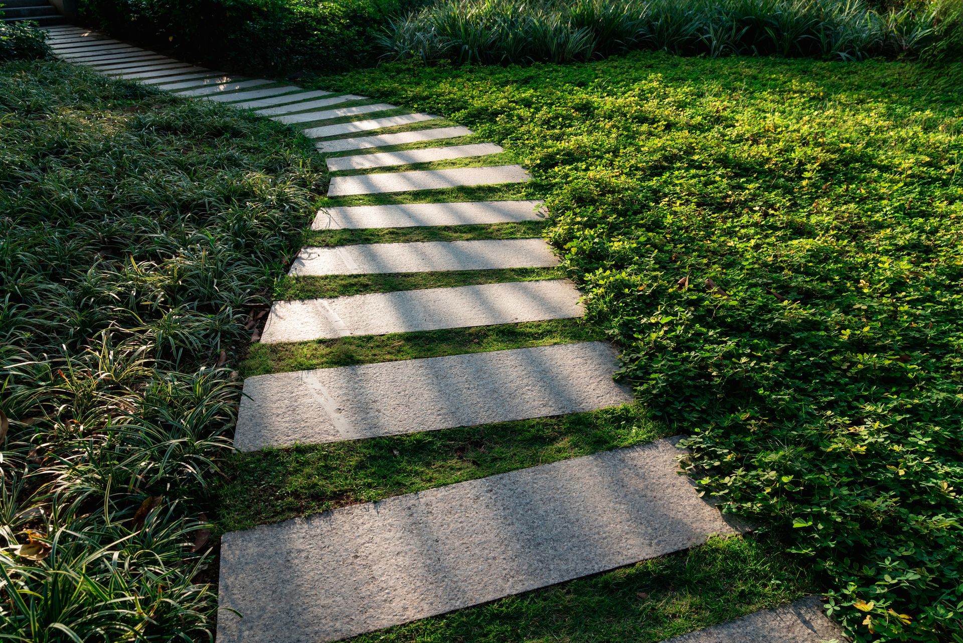 A stone walkway going through a lush green field.