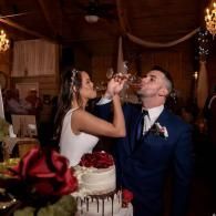 Bride and groom feeding each other cake at a wedding reception, with a tiered cake in the foreground.