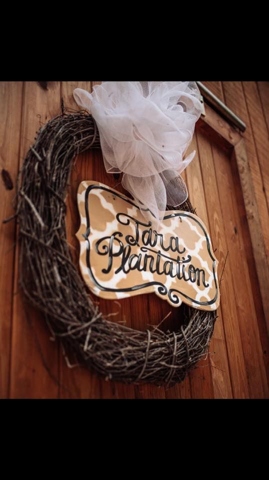 Wreath with a bow and rustic sign reading “Garden Plantation” on a wooden wall