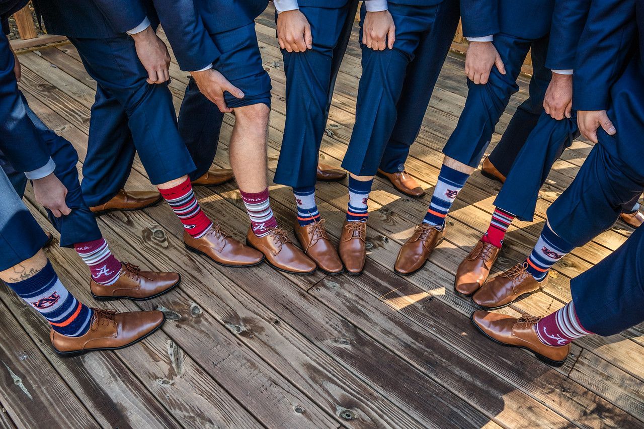 People in jeans and colorful socks standing in a circle on a wooden deck.