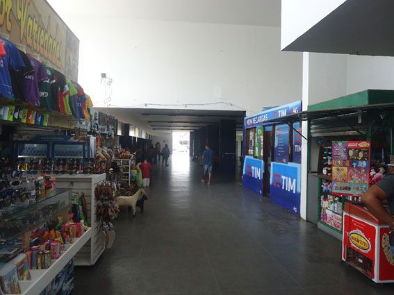 Homem na sala de controle falando ao telefone, supervisionando ônibus estacionados ao ar livre sob abrigo.
