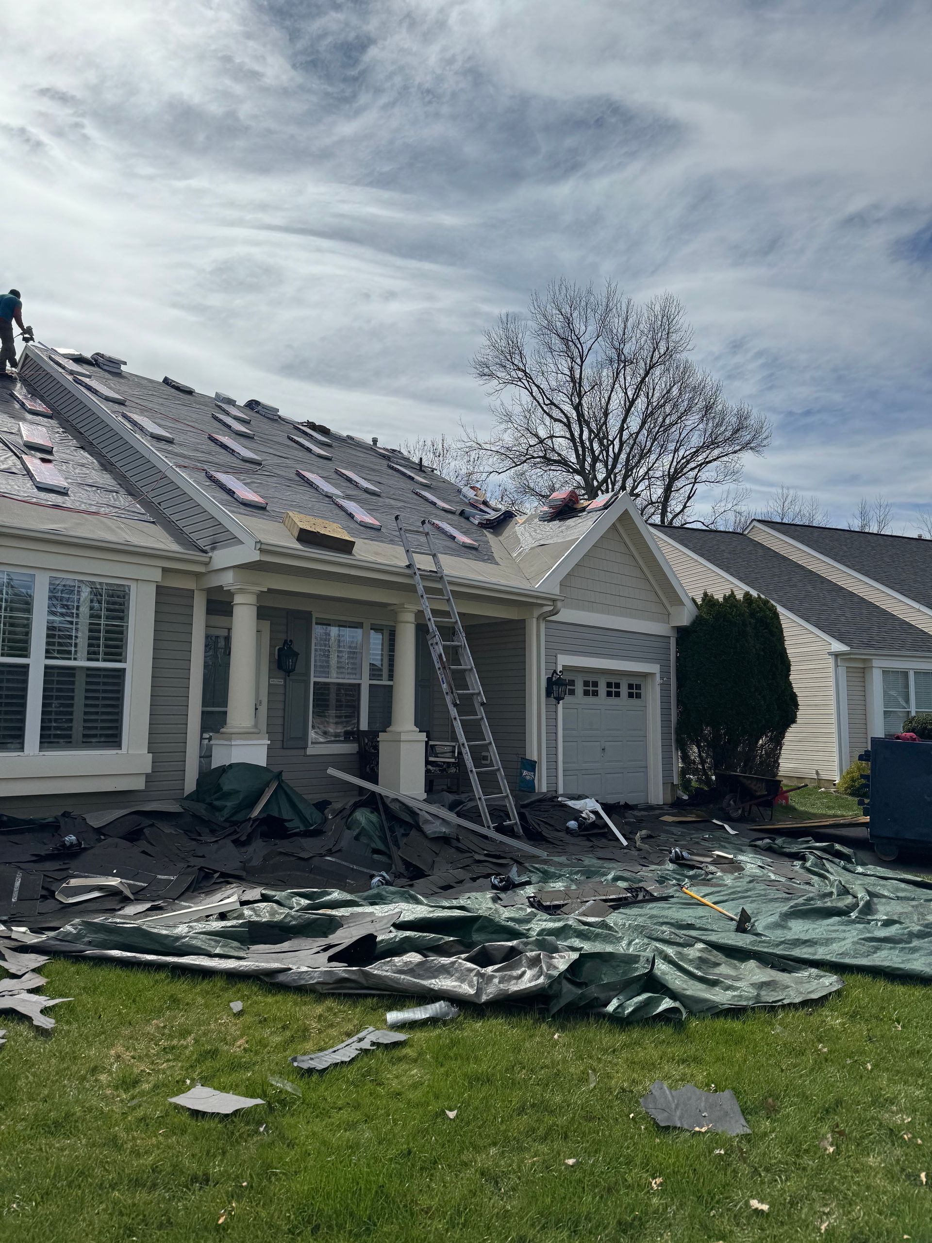 Damaged house with collapsed roof and debris strewn across the lawn after severe storm damage