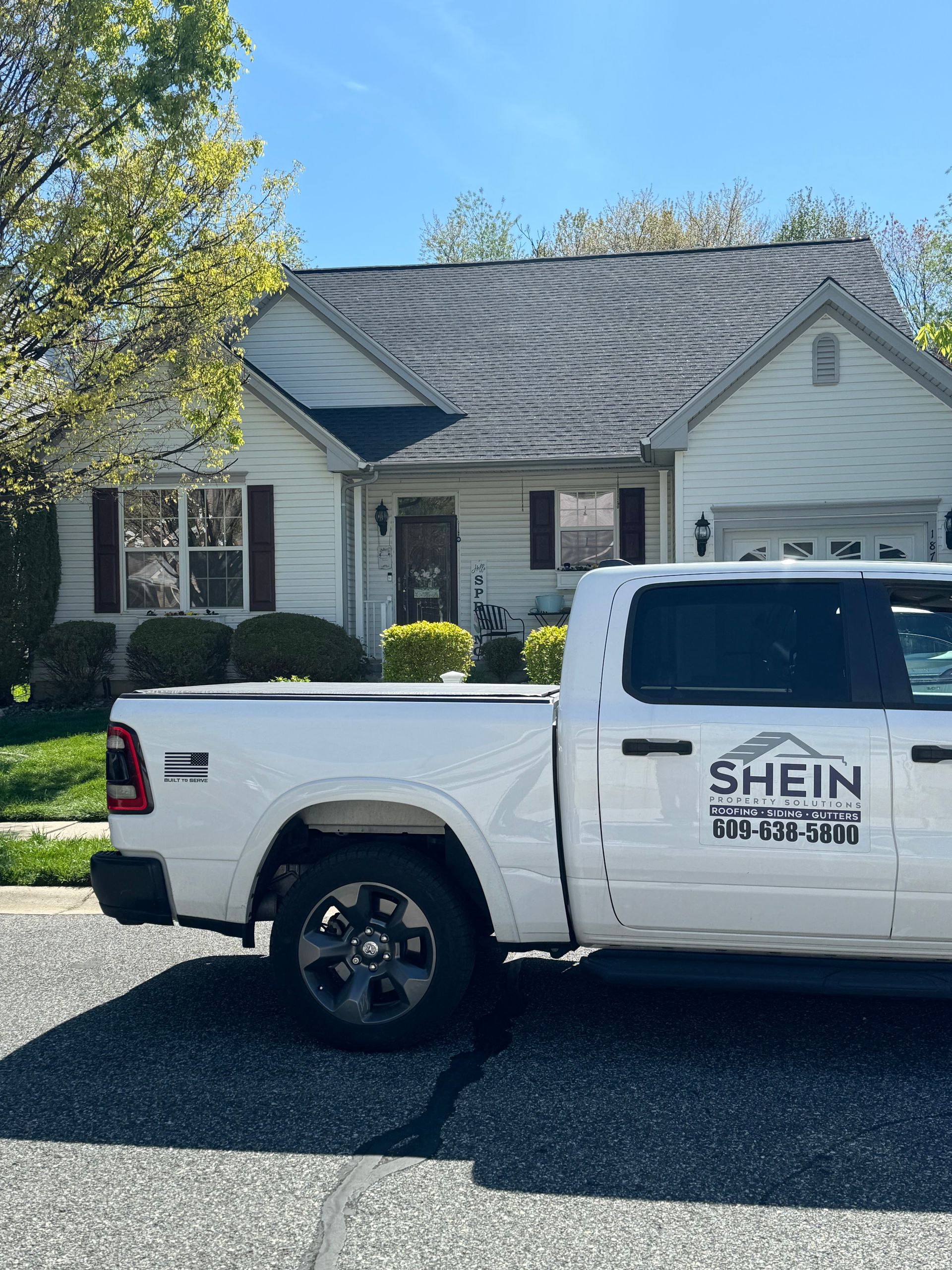 White SHEIN pickup truck parked in front of a gray suburban house on a sunny day