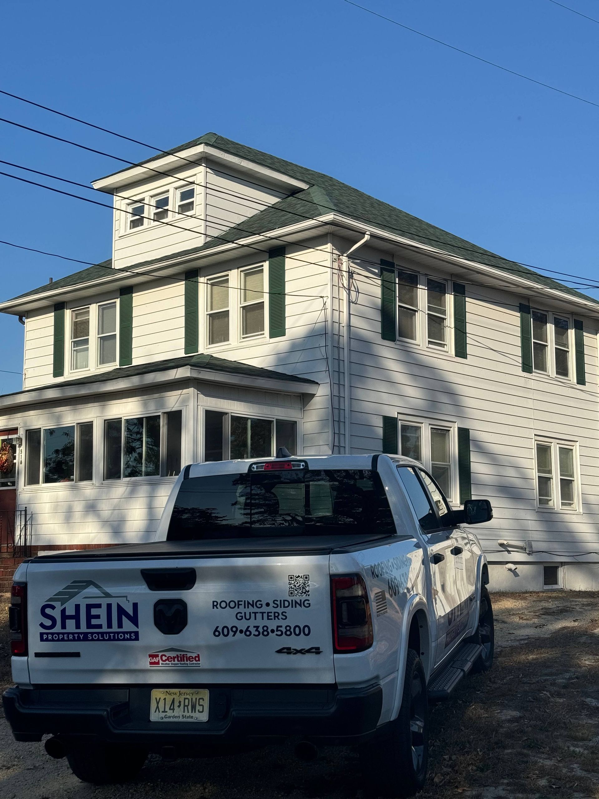 White house with green trim behind a pickup truck with a SHEIN logo on the tailgate.