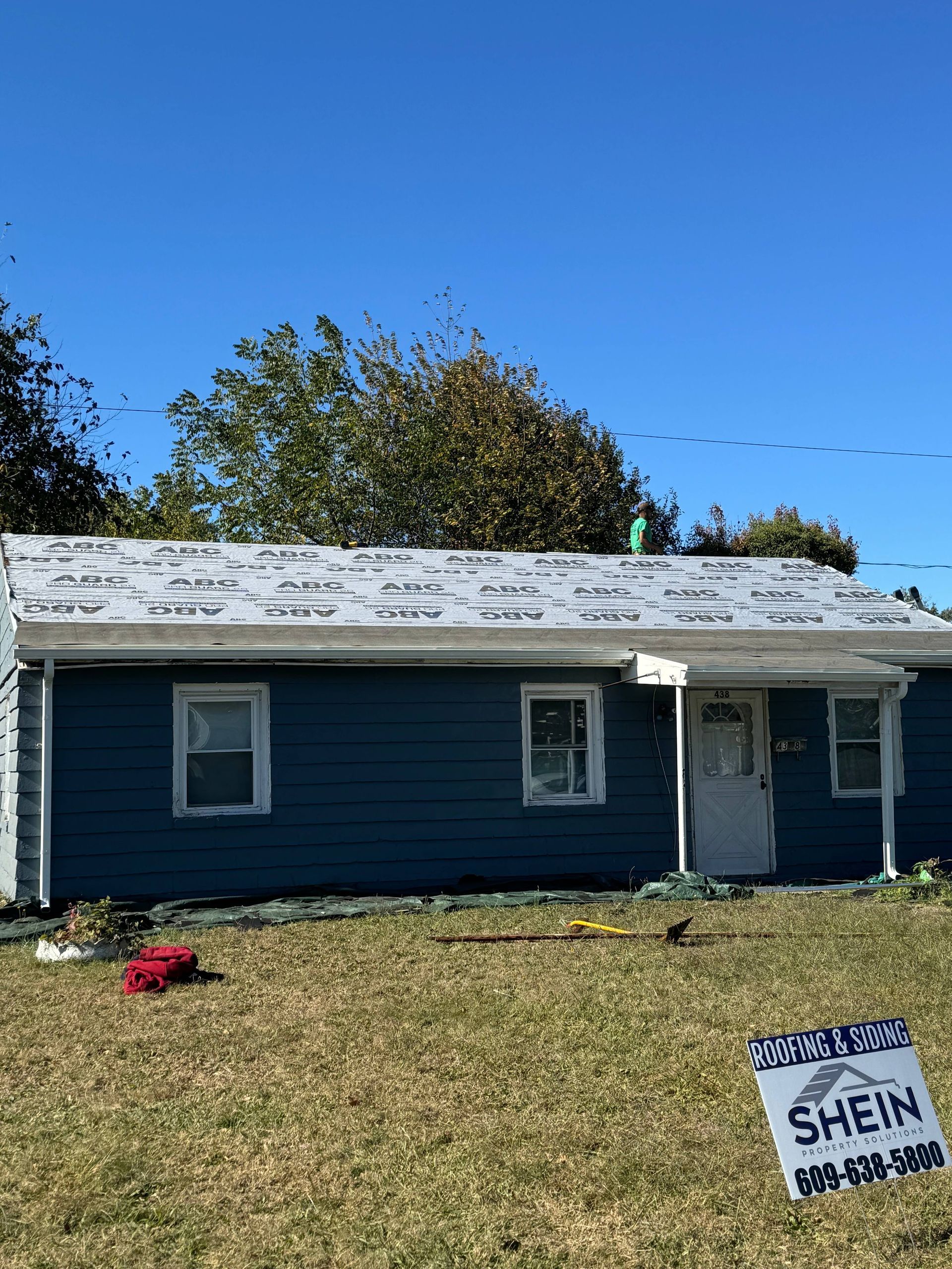 Small blue house with white trim under a clear sky; campaign sign in the front yard.