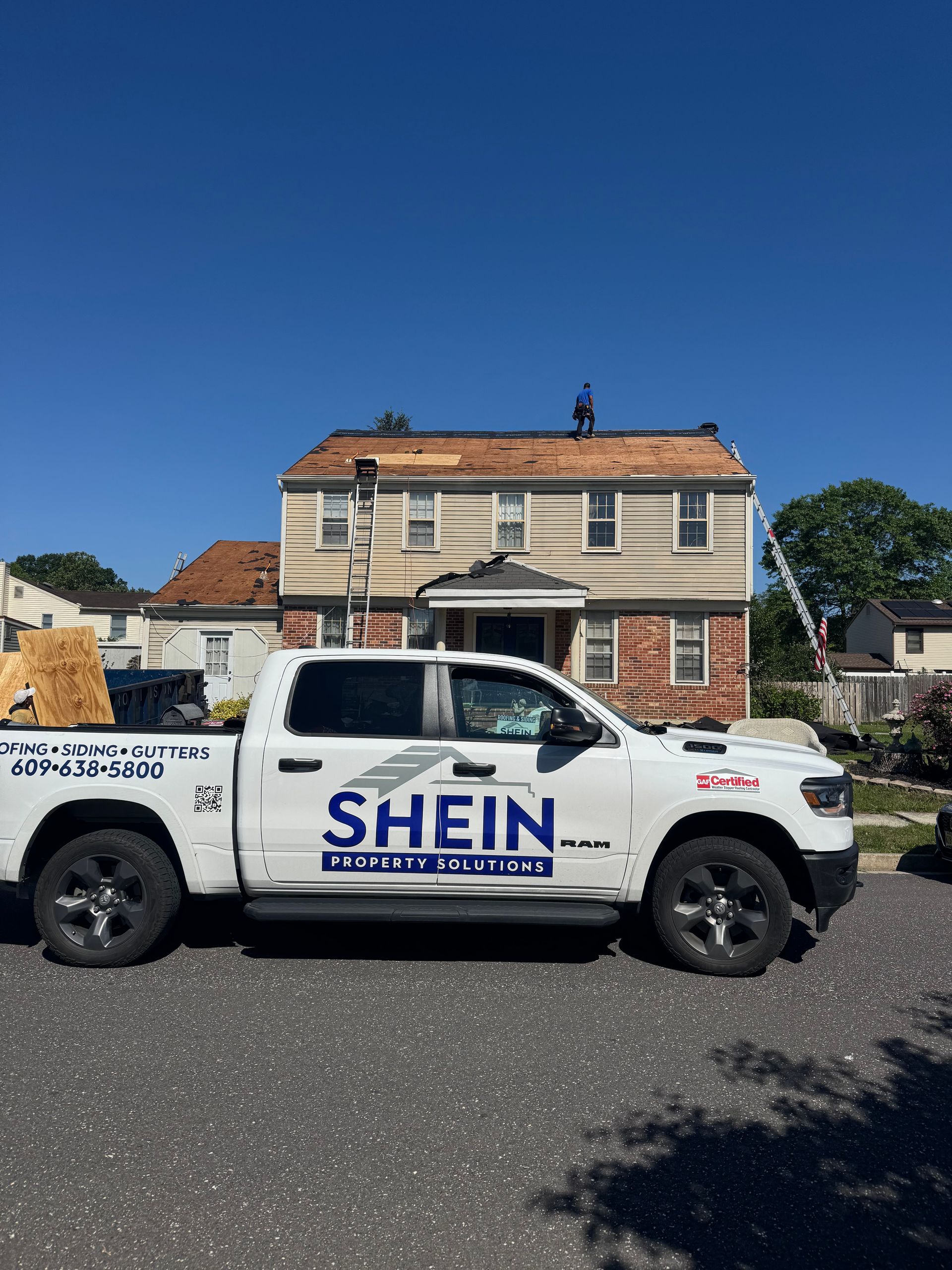 White SHEIN pickup truck parked in front of a beige house under a clear blue sky.