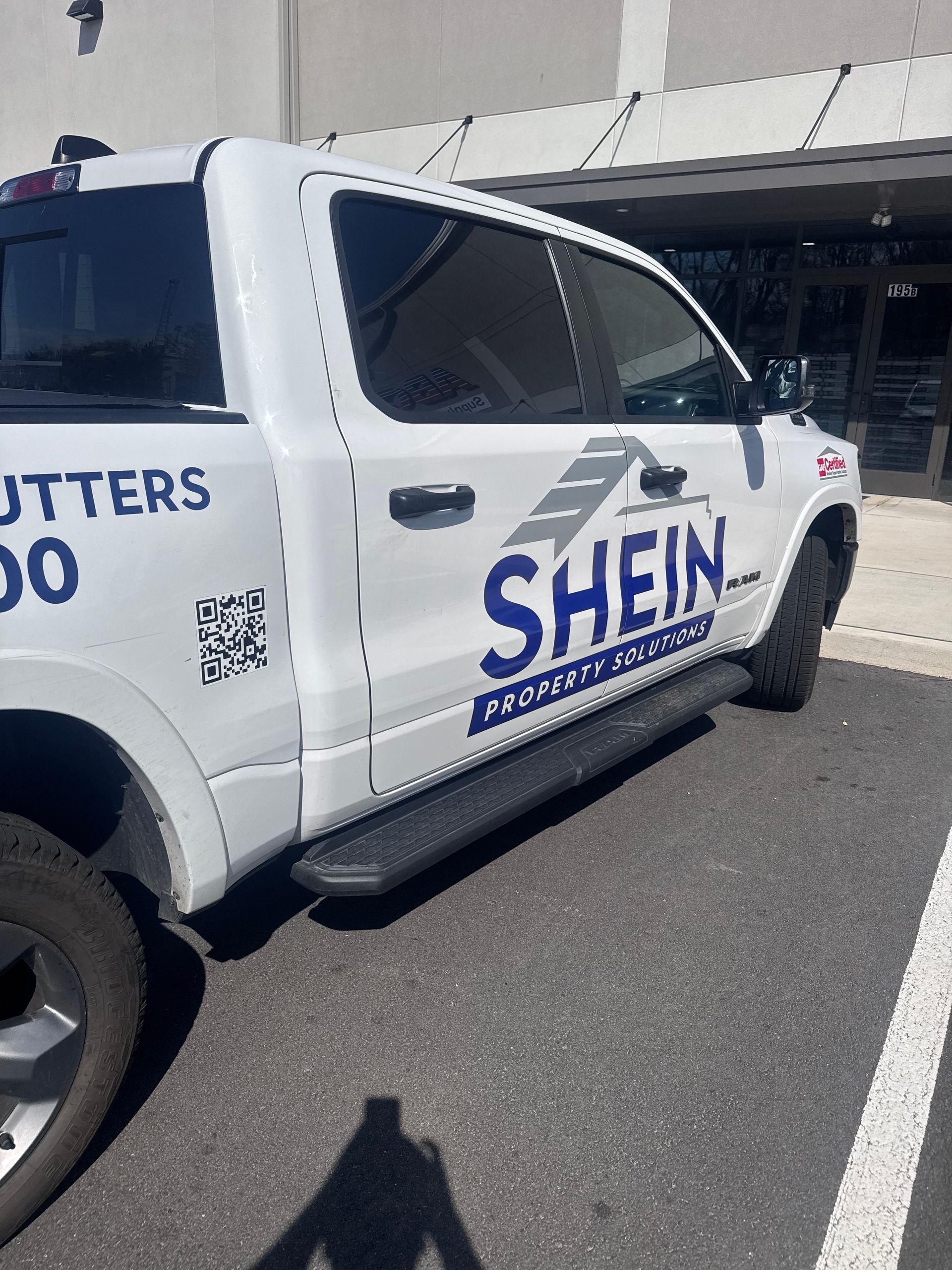 White SHEIN-branded pickup truck parked outside a building in a parking lot