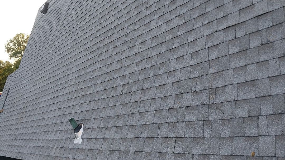 Gray shingled wall with a small damaged or open patch near the bottom left.