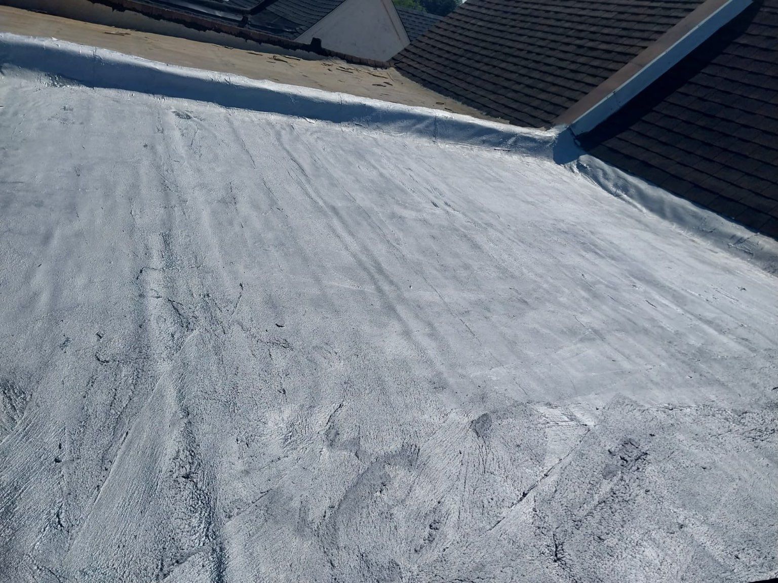 Snow-covered sloped roof with footprints and roof vents in the background