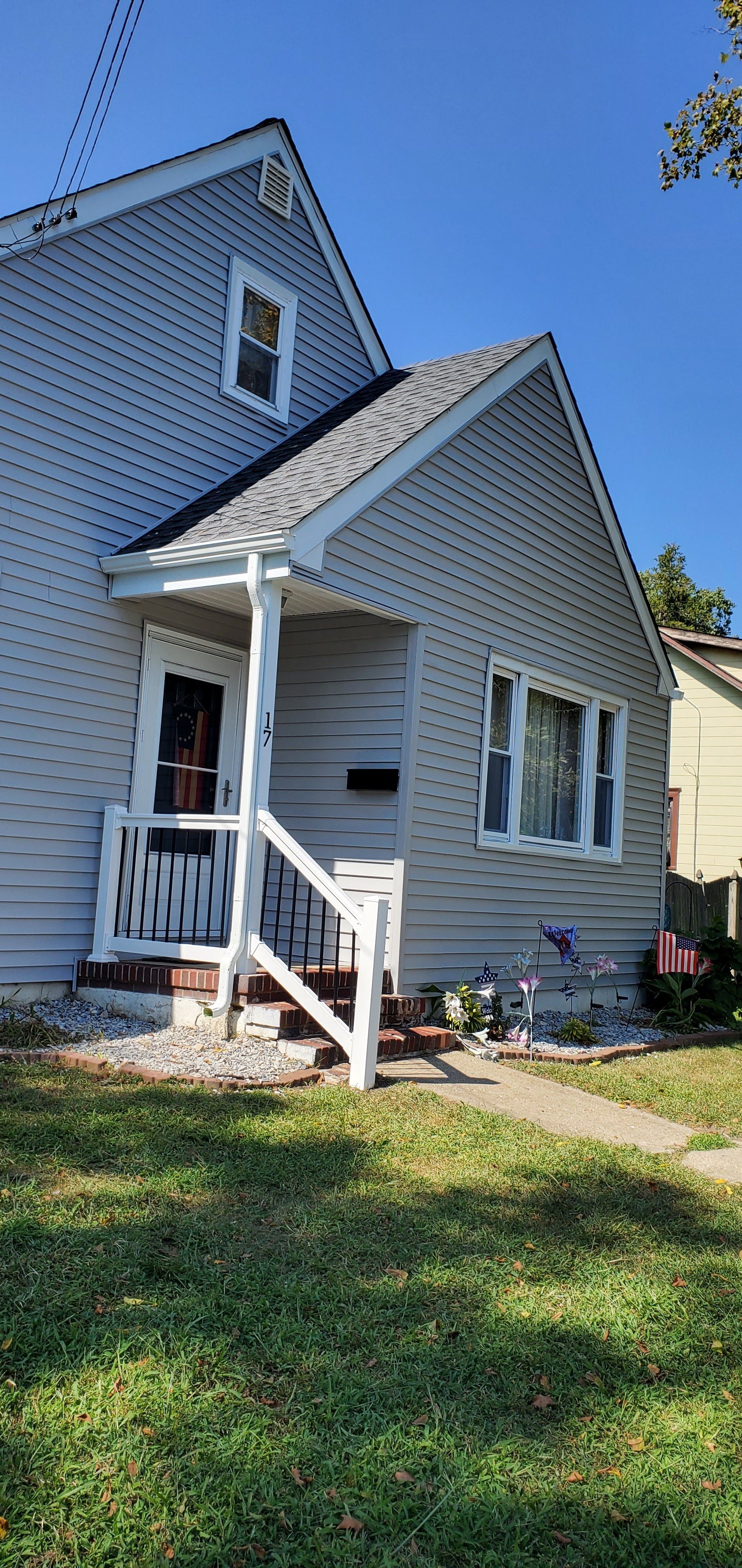 White house with blue trim and front porch in a sunny yard