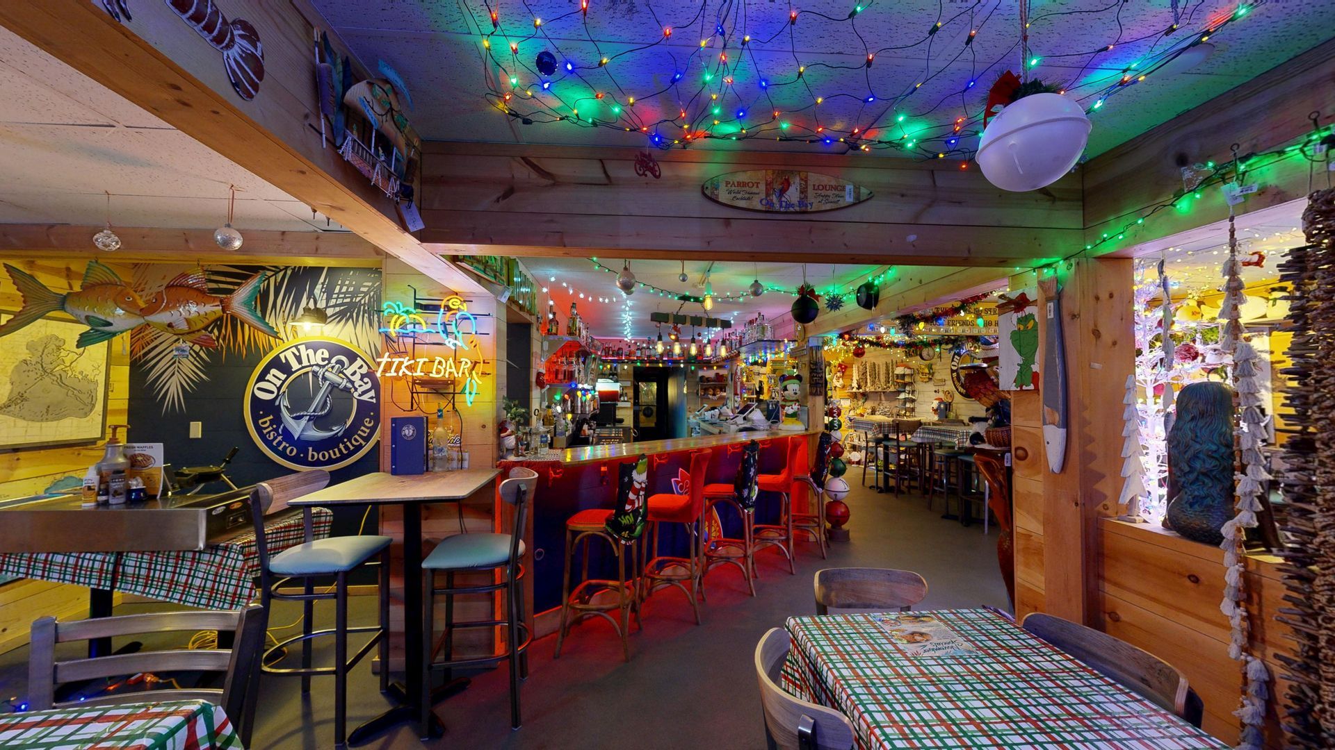Interior of a colorful bar with string lights. Red bar with stools, tables, and eclectic decor.