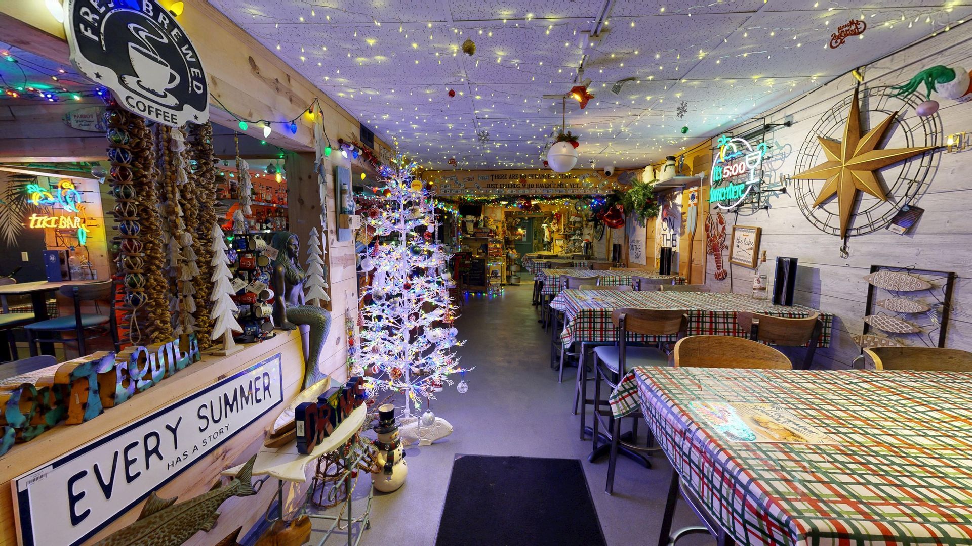 Coastal-themed bar interior with bar stools, counter, drinks, and a surfboard decoration; blue and white tones.