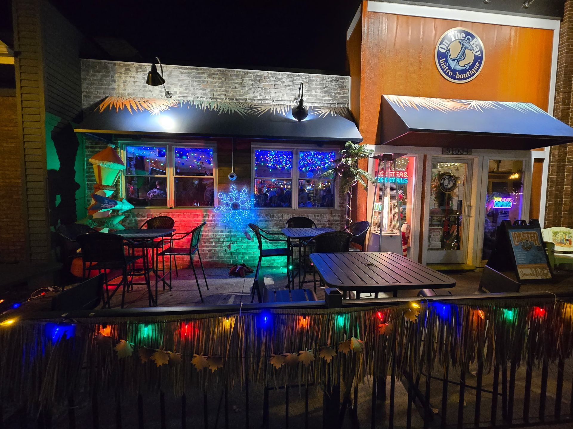 Restaurant exterior at dusk, with outdoor seating, brick, and blue accents.