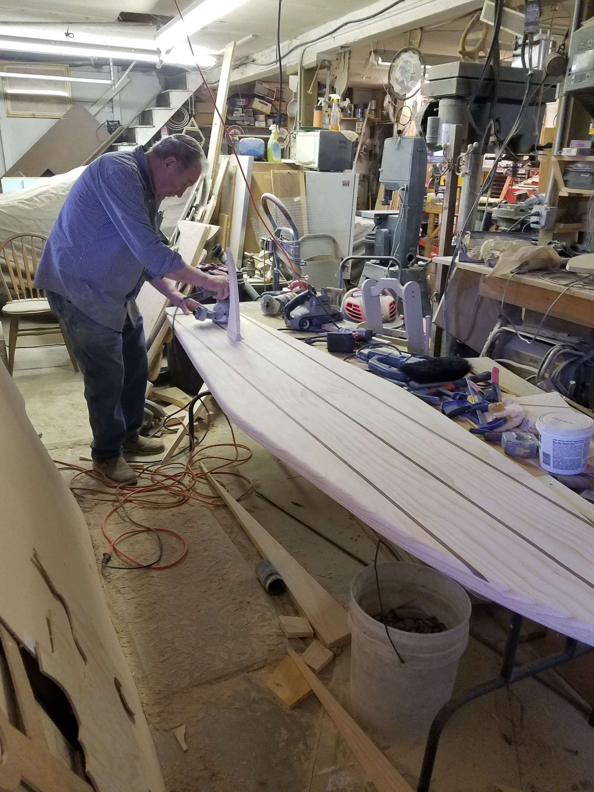 A man is working on a surfboard in a workshop