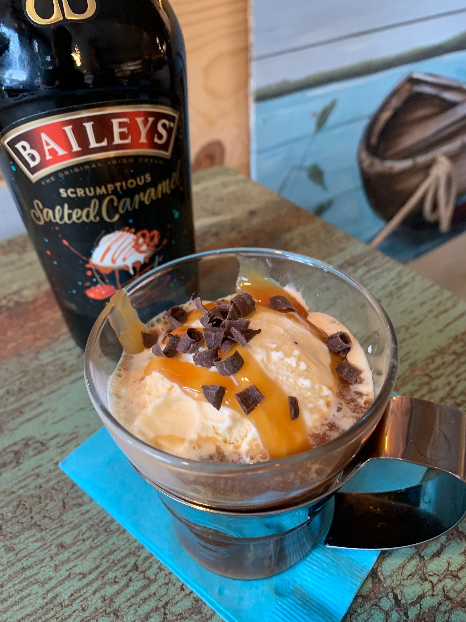 A bottle of baileys next to a glass of ice cream