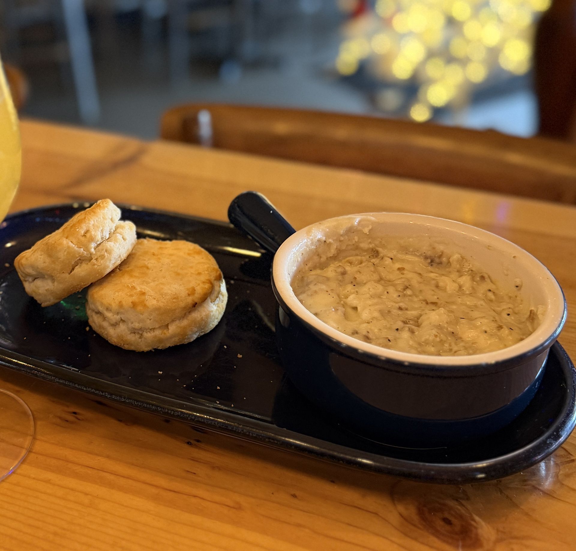 Biscuits and sausage gravy on a blue plate, set on a wooden table.