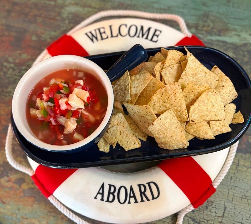 A welcome aboard life preserver with a bowl of salsa and chips on it