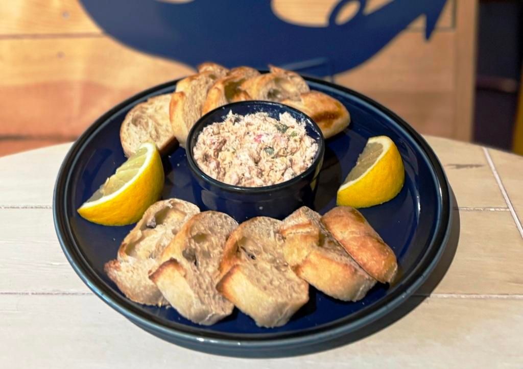 A plate of food with bread , dip and lemons on a table.