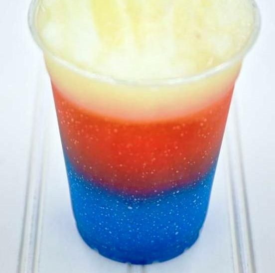 Red, white, and blue layered frozen drink in a clear plastic cup.