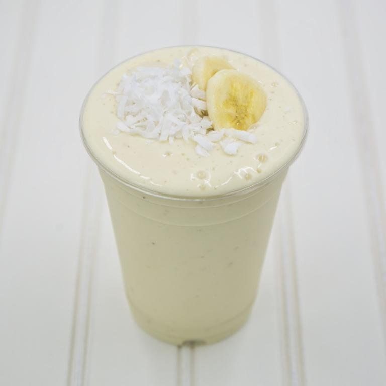 Banana coconut smoothie in a clear plastic cup, topped with banana slices and shredded coconut.