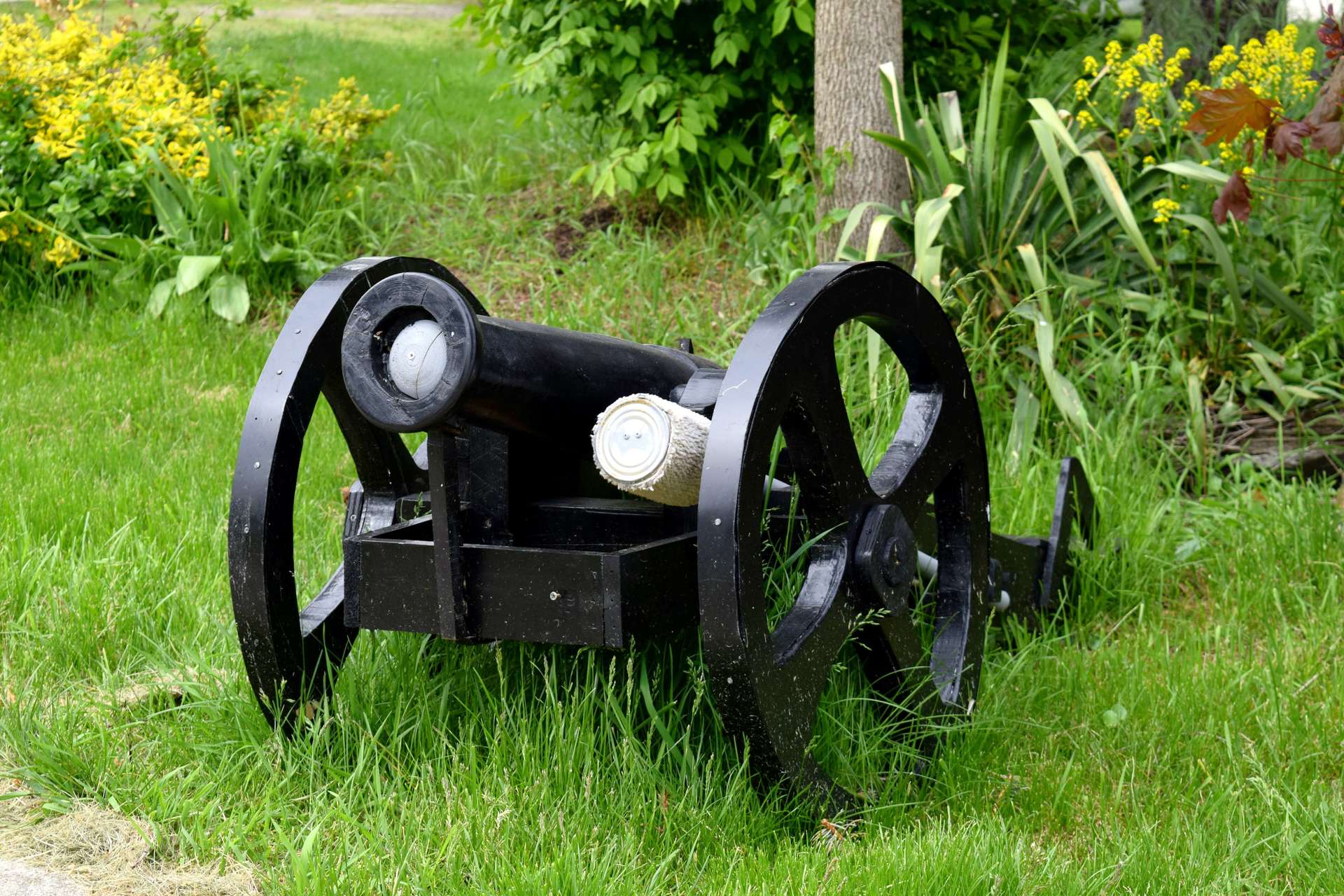 A small black cannon is sitting in the grass