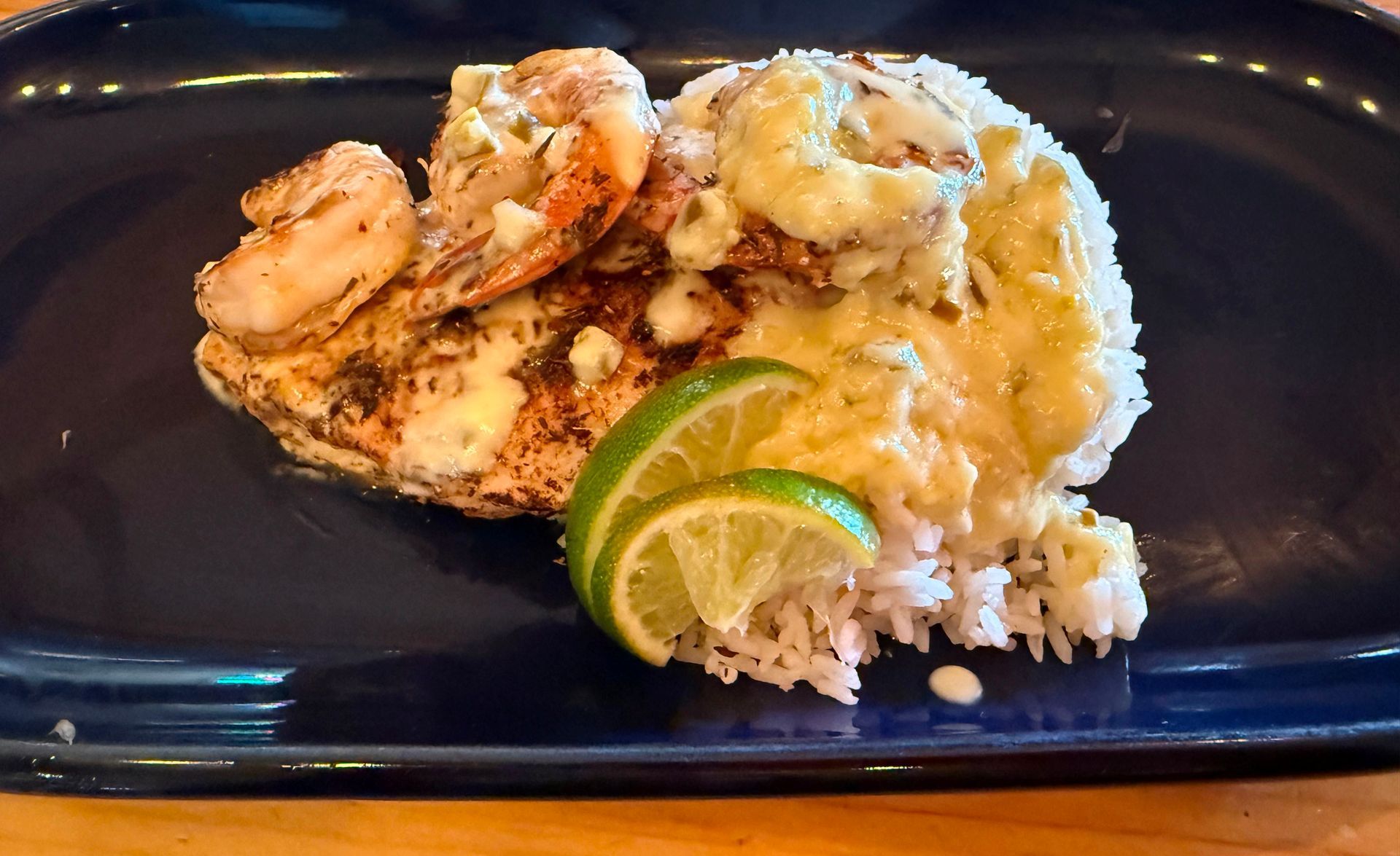 Grilled shrimp and fish with rice, lime slices on a blue plate.