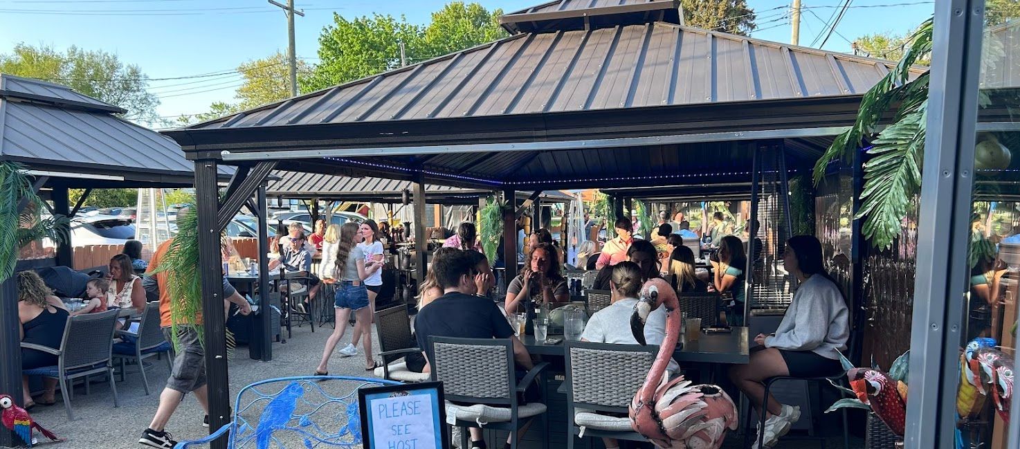 A group of people are sitting at tables under a gazebo.