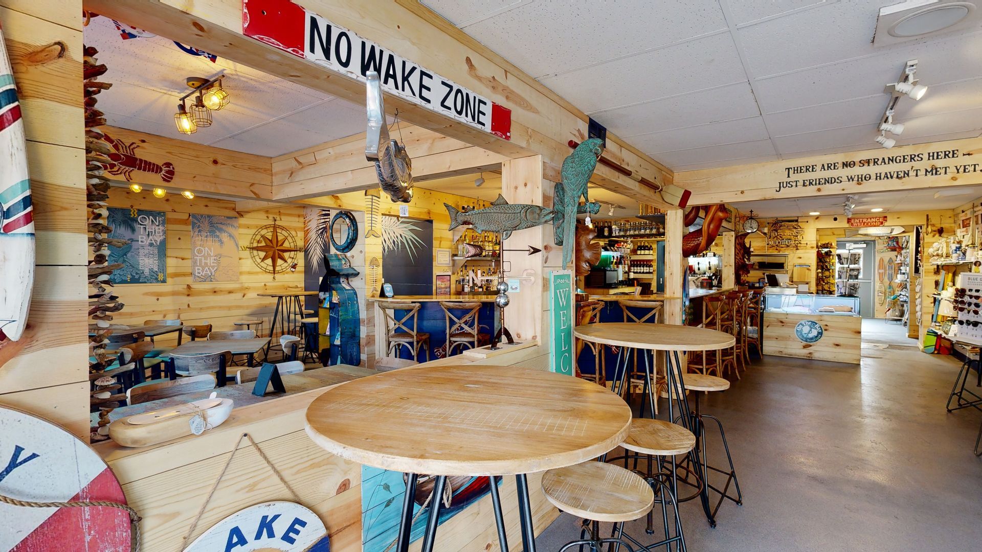 At On The Bay restaurant with indoor dining, tiki bar and a nautical boater boutique with a sign that says No Wake Zone.