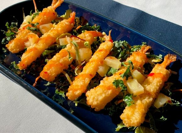 A blue plate topped with fried shrimp and vegetables