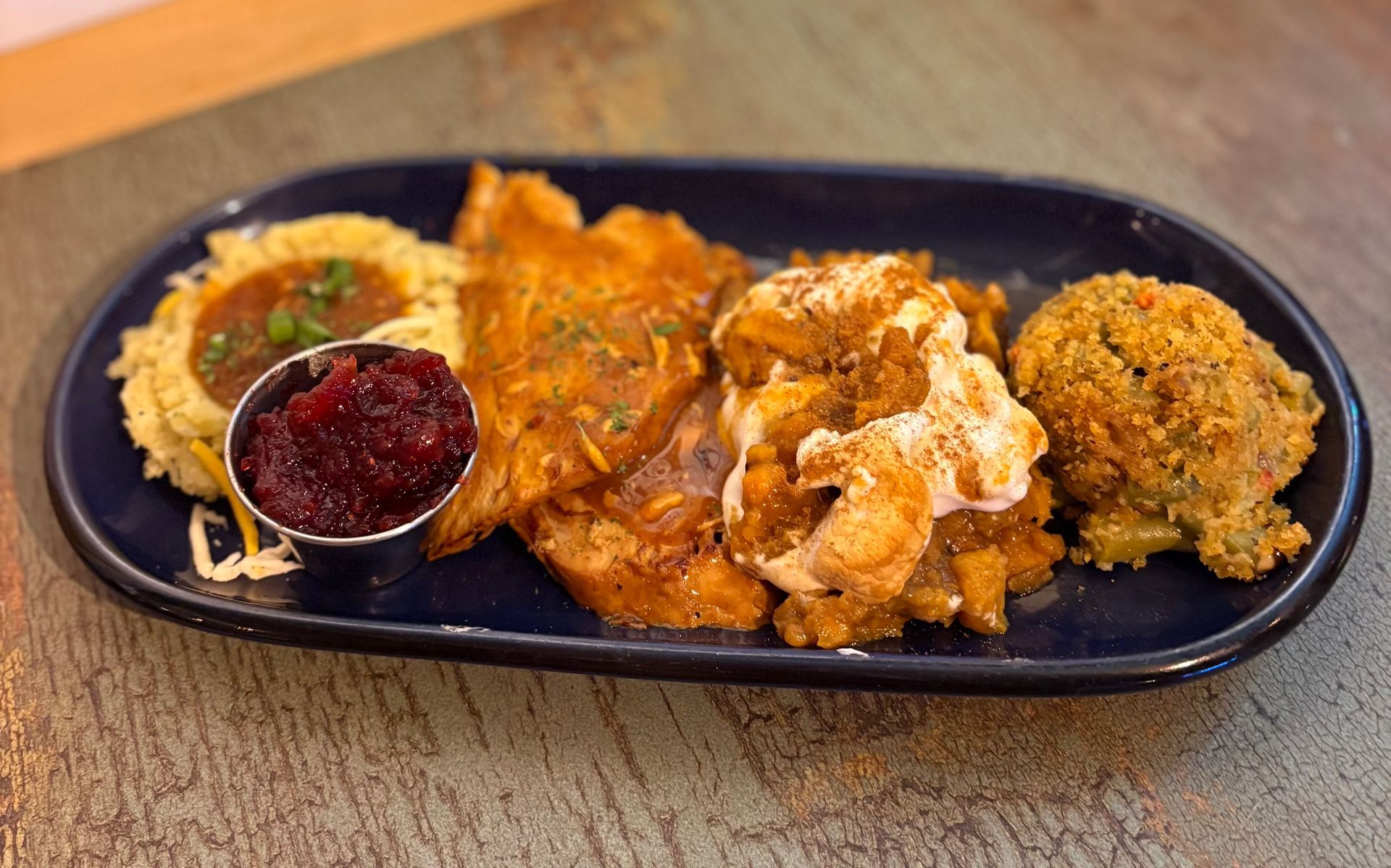 Plate of food with various components, including stuffing, mashed potatoes, and fried cauliflower.