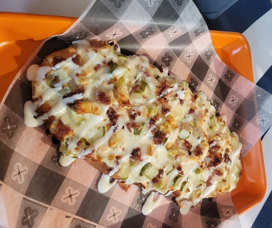 A close up of a pizza on a checkered napkin on an orange tray