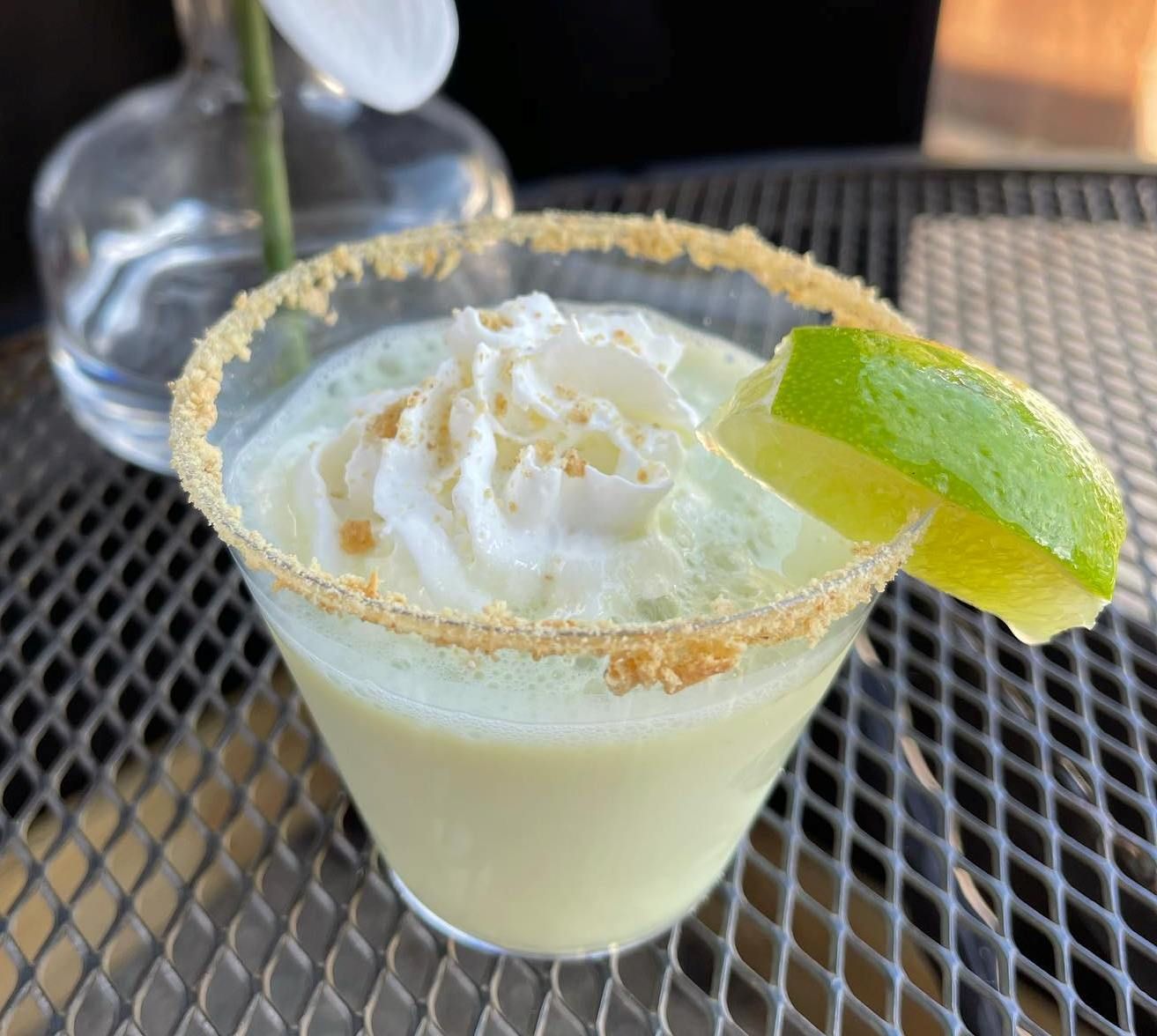 A margarita with whipped cream and a slice of lime on a table