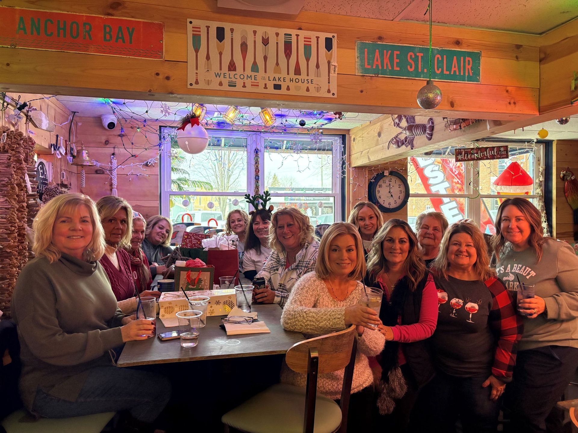 Group of women smiling, gathered around a table in a bar decorated with nautical signs.