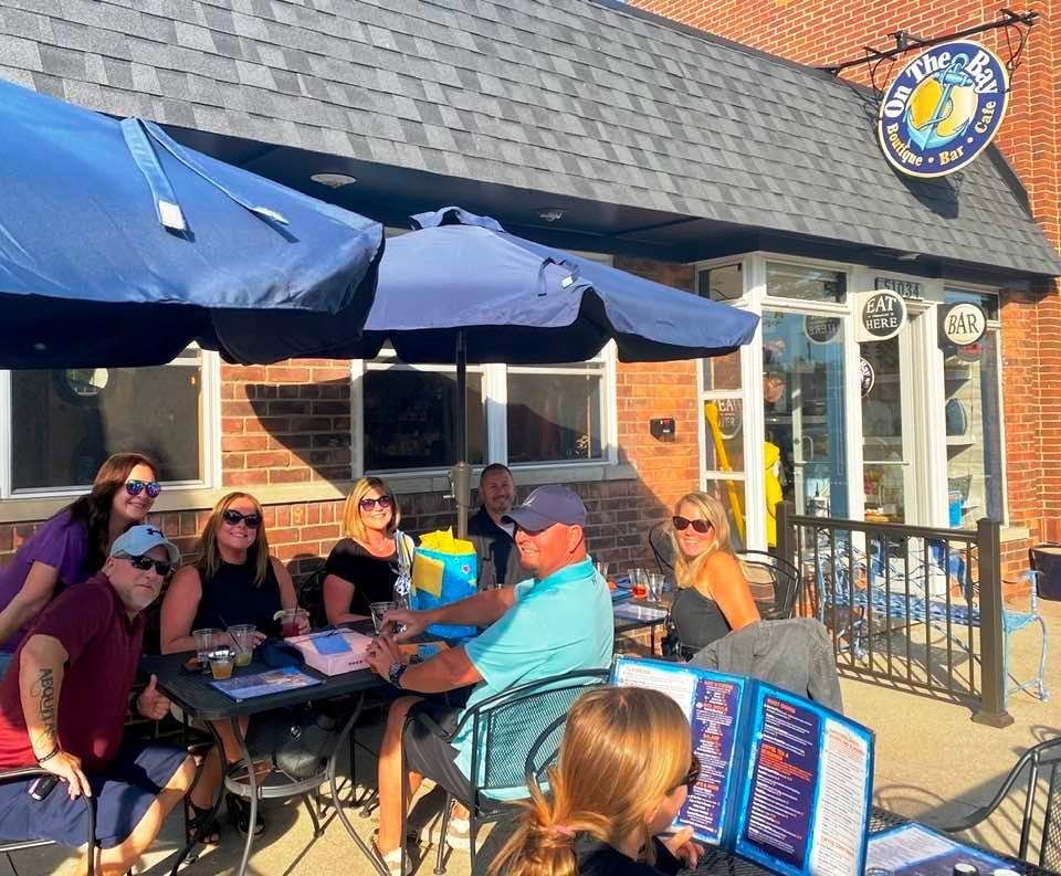 A group of people are sitting at tables under blue umbrellas outside of a restaurant.