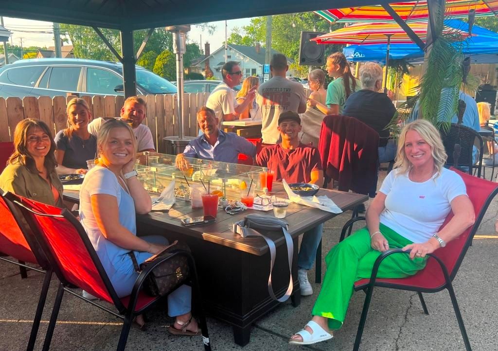 A group of people are sitting at a table under an umbrella.