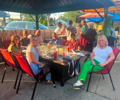 A group of people are sitting around a table under an umbrella