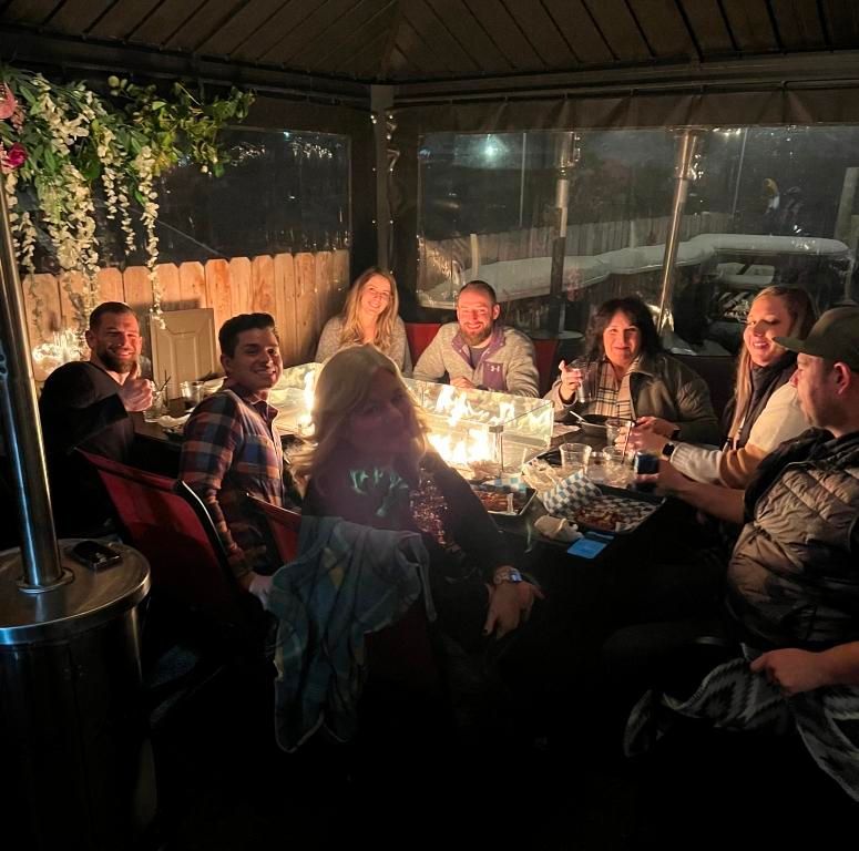 A group of people are sitting around a table at night